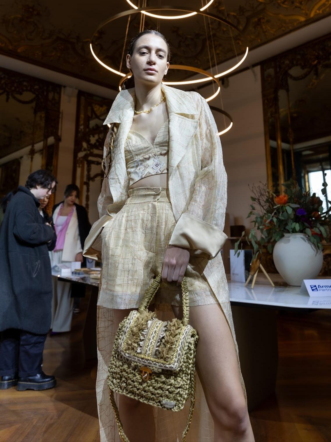 Model u krem odjevnoj kombinaciji nosi Bella Mandorla torbu u zeleno-zlatnim tonovima na showroom izložbi tijekom Milan Fashion Weeka